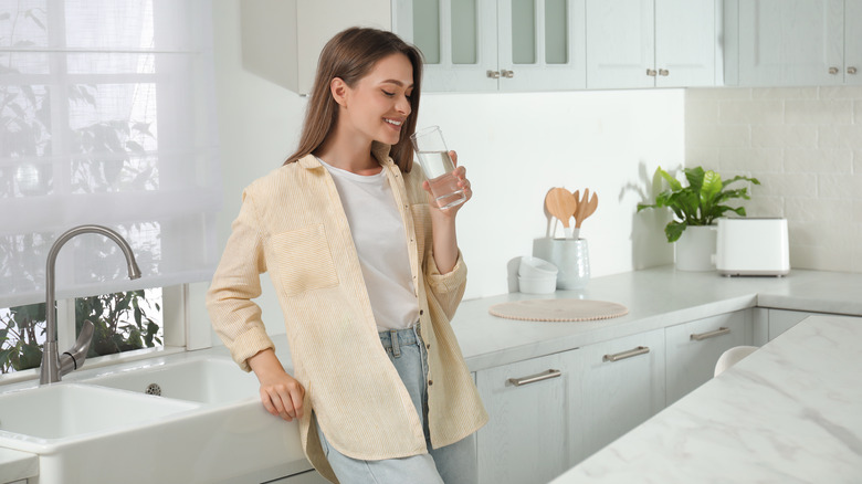 Woman drinking a glass of water in the kitchen