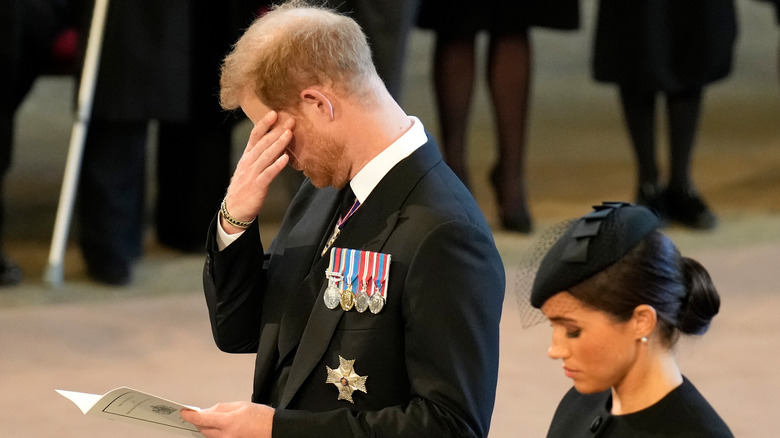 Prince Harry holding hand to face 