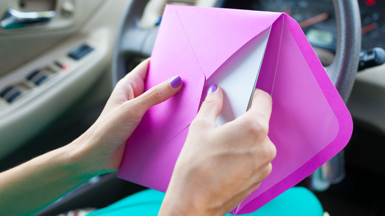 Woman in car with pink envelope