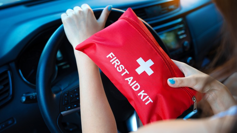 Woman holding first-aid kit in car