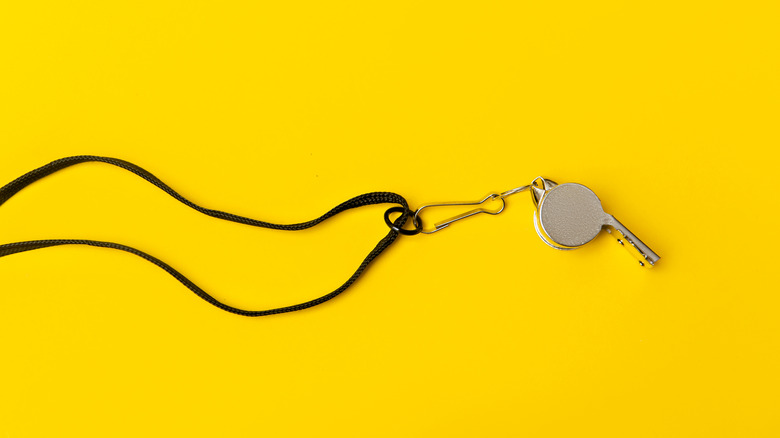 Metal whistle on yellow background