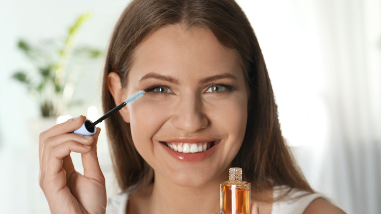 woman applying oil to lashes