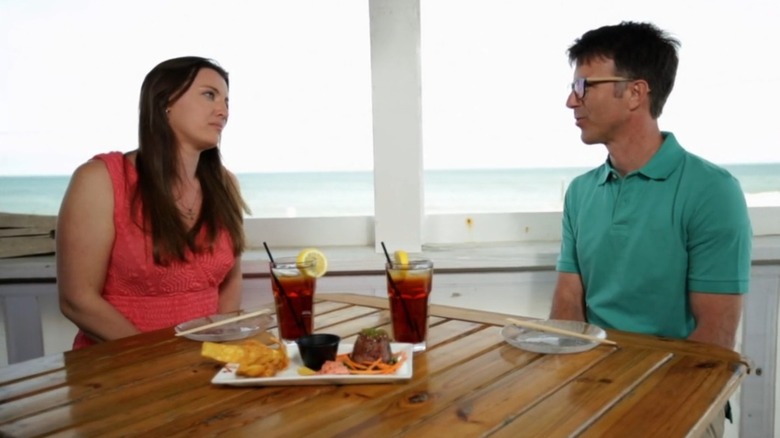 Johanna and Andy sitting at a seaside table on "Beachfront Bargain Front"