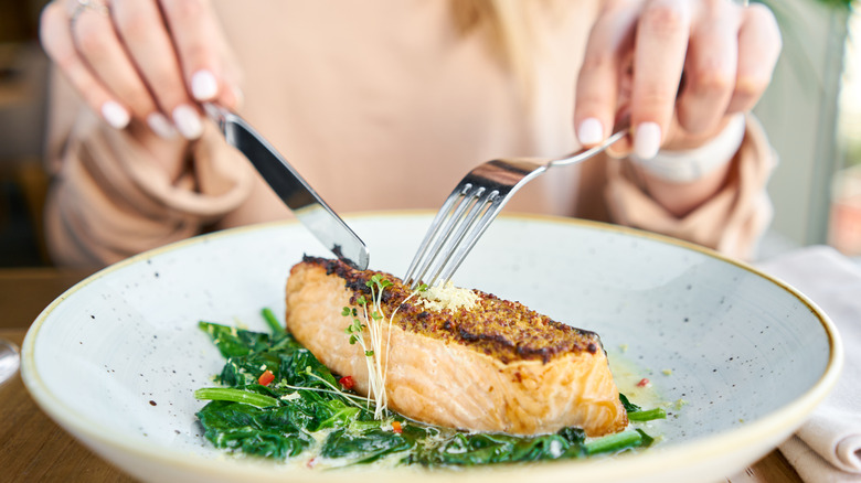 woman cutting into salmon