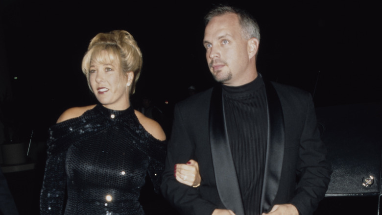 Garth Brooks and Sandy Mahl wearing all-black outfits and walking arm-in-arm