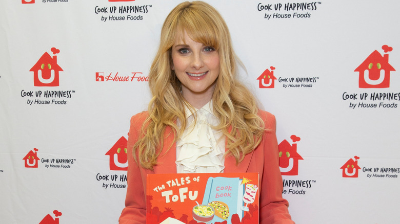 Melissa Rauch posing with children's book on red carpet