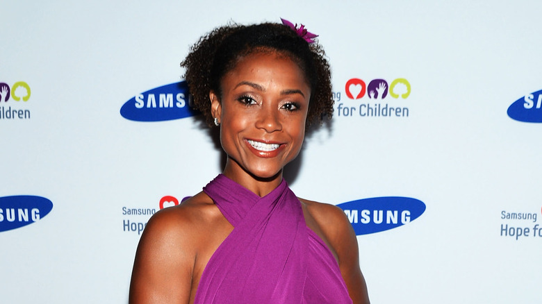 Dominique Dawes smiling in a purple dress 