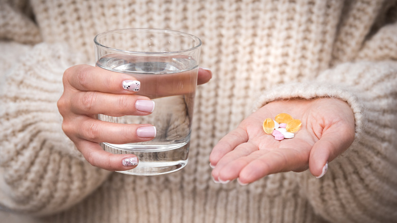 Hand holding pills and water