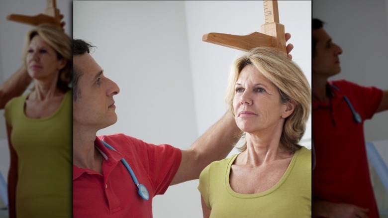 doctor measuring older woman's height