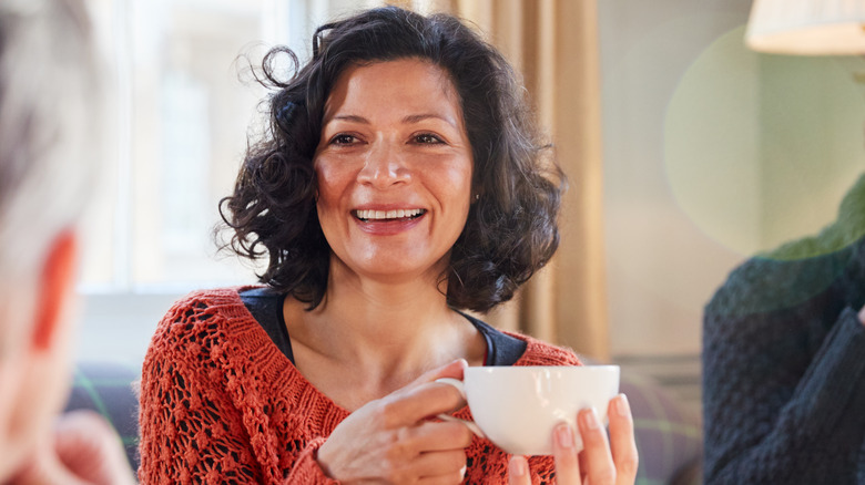 middle-aged woman smiling holding teacup