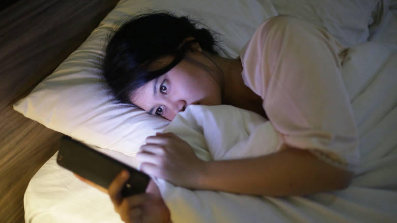 A woman in bed on her phone