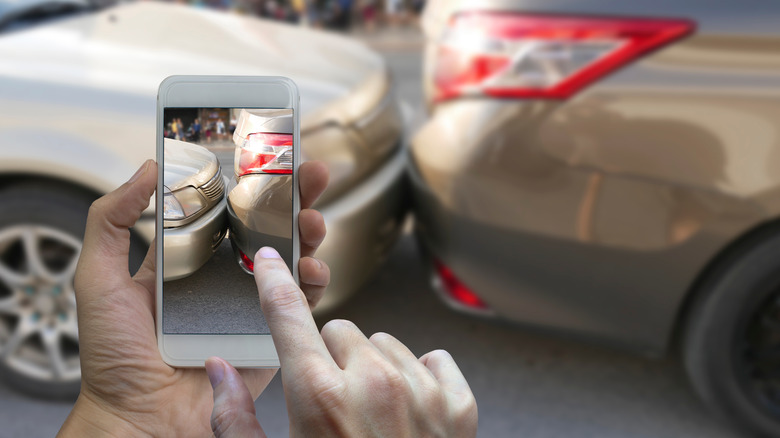 A hand taking photos of a fender bender after daylight savings time