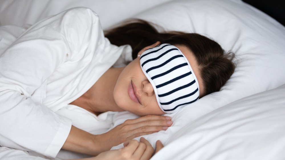 A woman asleep in bed with an eye mask