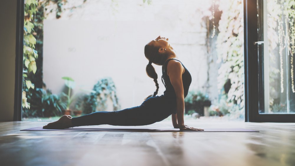 A woman holding cobra pose near a garden