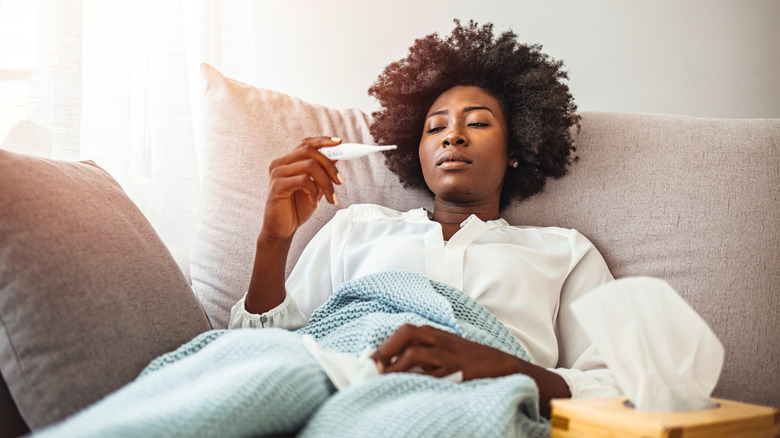 sick woman holding thermometer