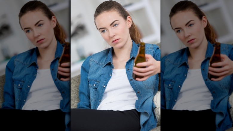 Woman sitting on couch holding beer