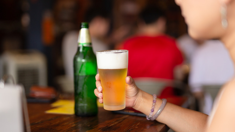 Woman holding beer glass at bar