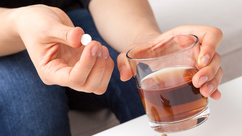 Person taking medicine with whiskey