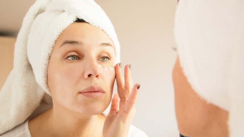 woman with dry skin applying moisturizer