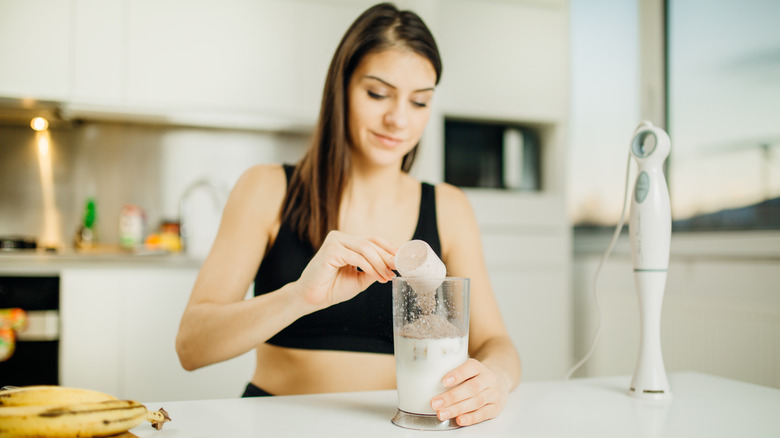 Woman scooping fitness drink pre workout smoothie