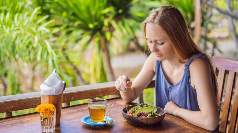 A woman eating a salad with beans and vegetables