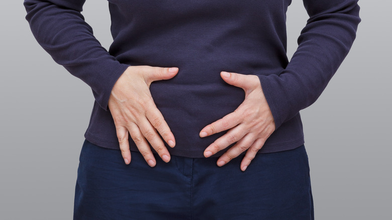 A woman with hands on her abdomen