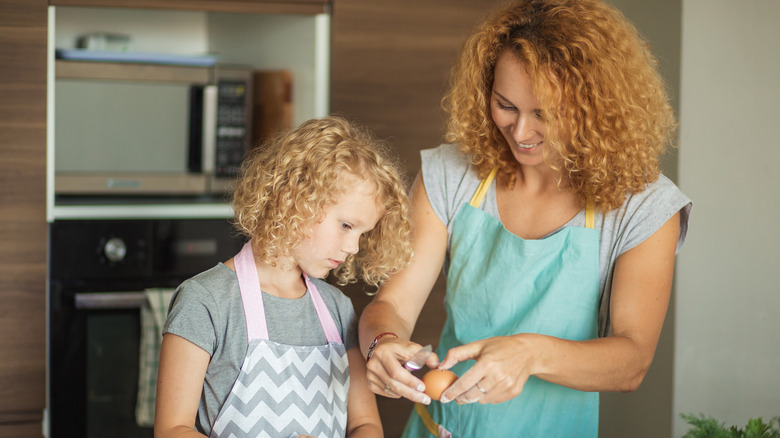 Mom and daughter cracking eggs