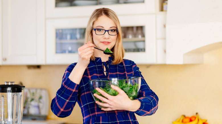 A woman eating a kale salad