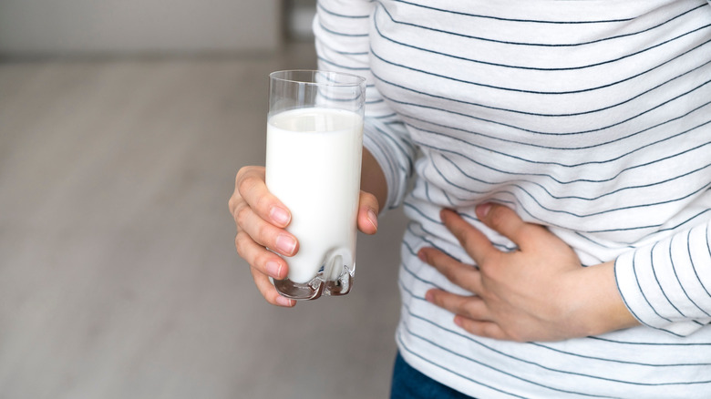 Woman holding stomach and glass of milk