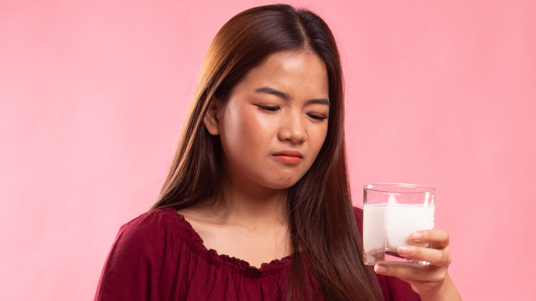 Woman looking at glass of milk disappointedly