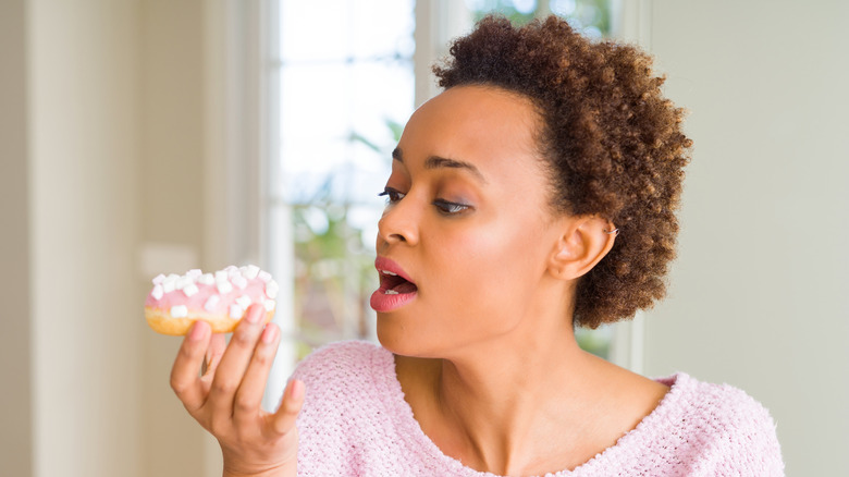 A woman eating a doughnut and having too much sugar