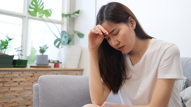 A depressed woman sitting on a couch after eating too much sugar