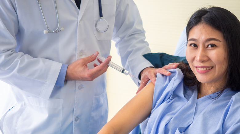 A woman getting a flu shot, smiling