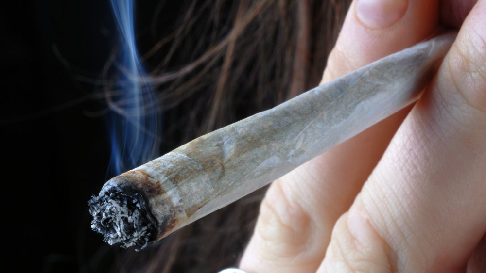 Close up of a woman's hand holding a lit joint