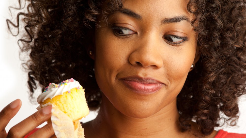 A woman looking at a cupcake