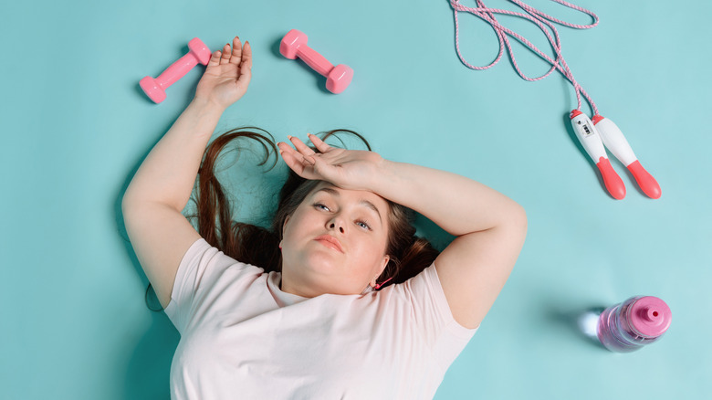 Woman lying on the floor looking tired after a workout