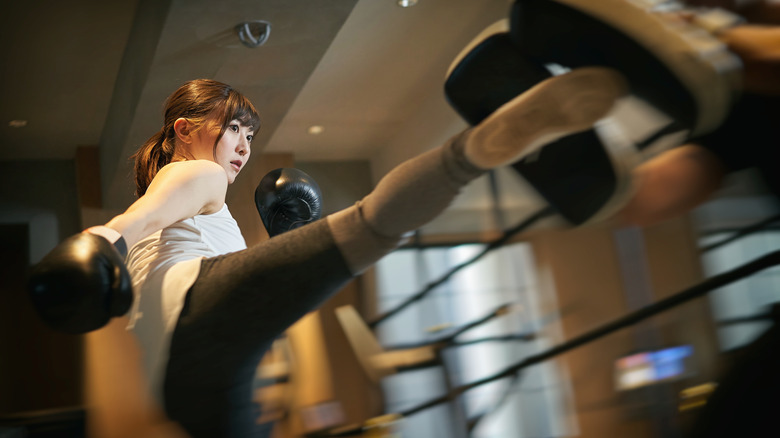 A woman kicks pads