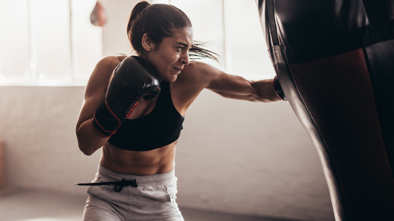 A woman wearing black boxing gloves