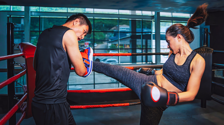 A woman kicks pads