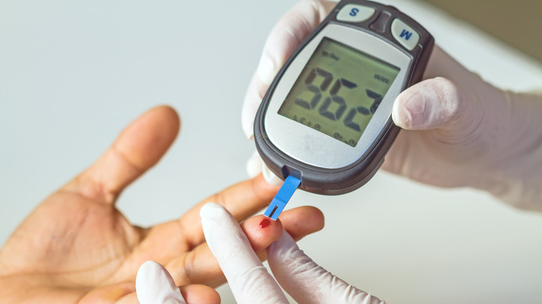 Gloved hands measuring someone's blood sugar levels