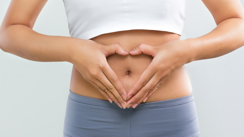 A woman making a heart shape with her hands over her abdomen