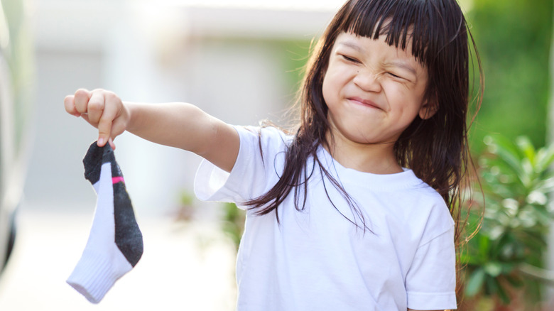 Young girl holds smelly sock