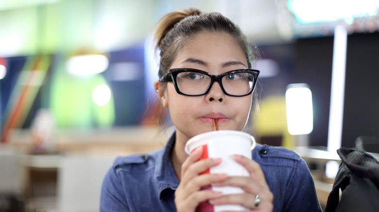 A woman drinking soda out of a cup