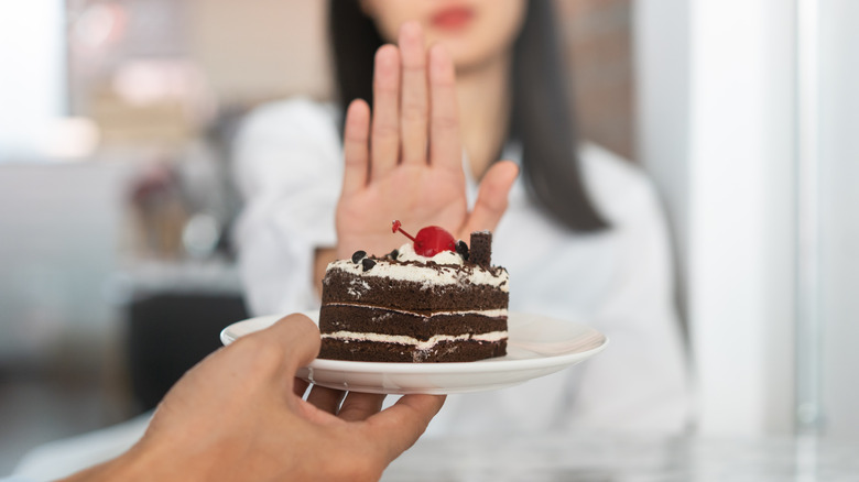 A woman refusing a slice of cake