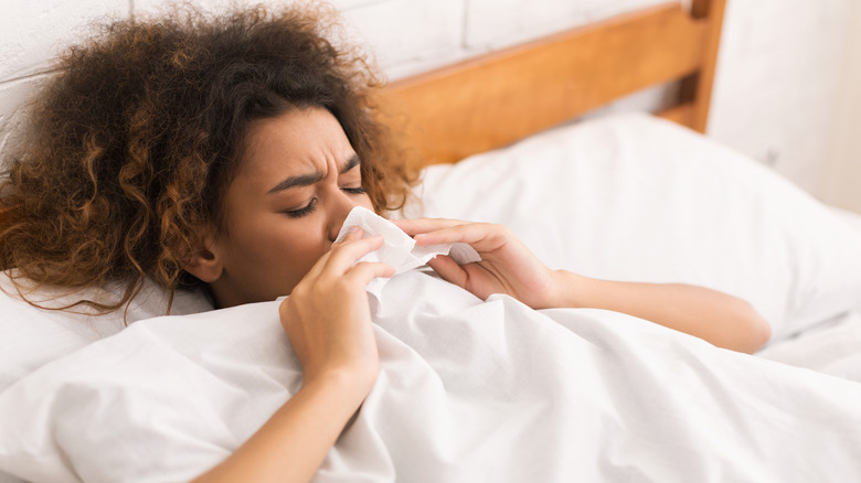 A woman in bed blowing her nose