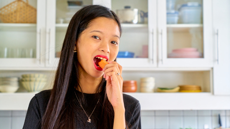 A woman eating a carrot