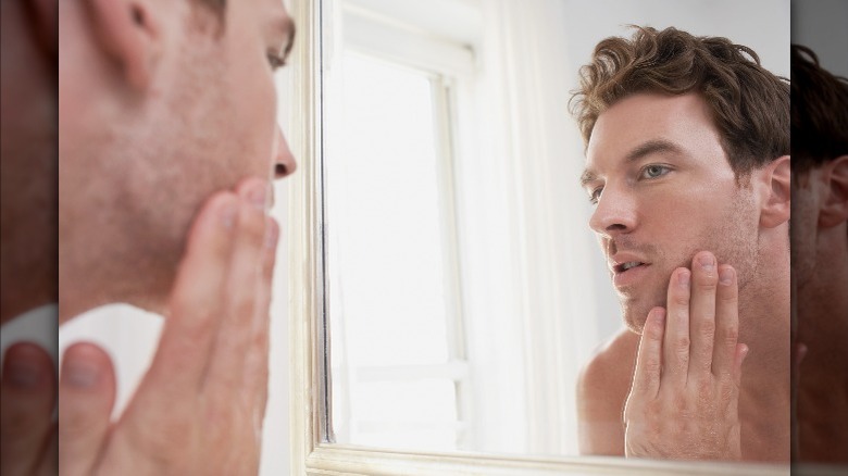 Man stares at face in mirror