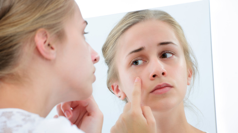 Woman examines face in mirror