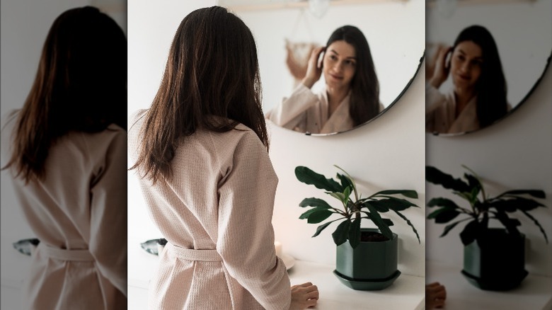 Woman looks in round mirror