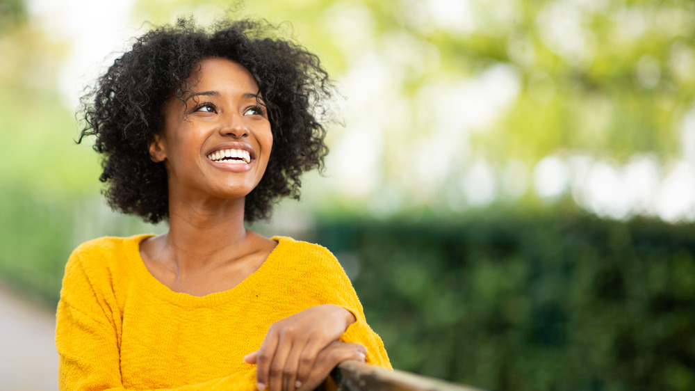 A woman sitting outside grinning